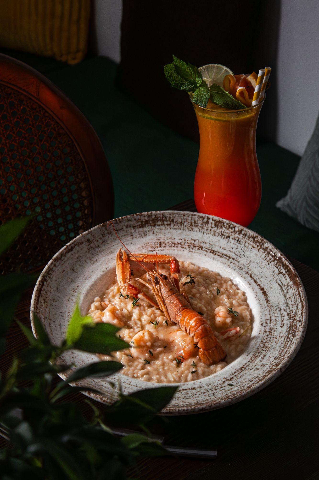 Risotto z krewetkami w kremowym sosie, z soczystymi krewetkami na wierzchu, obok kolorowy koktajl.