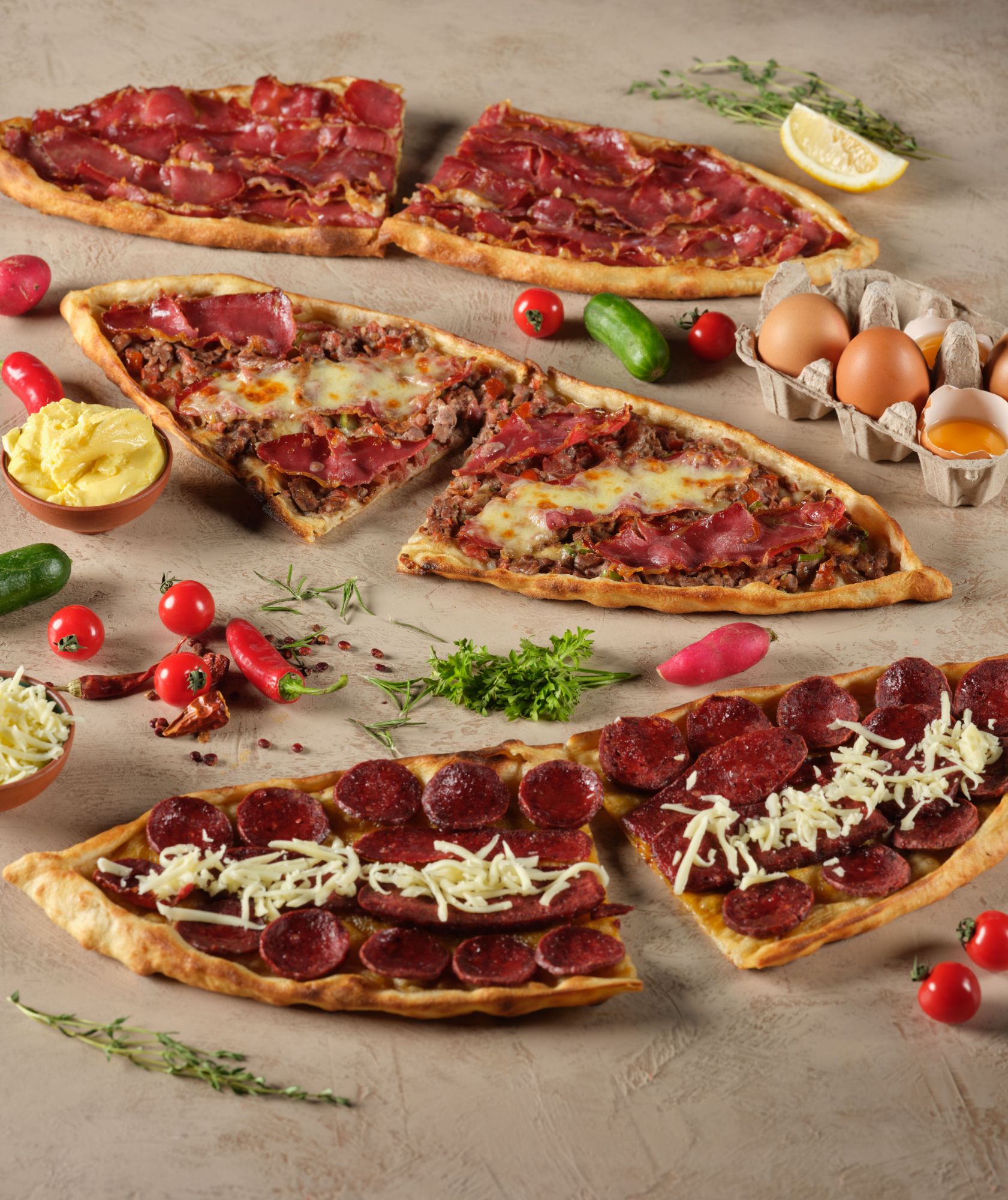 Pizza z różnymi dodatkami, w tym pepperoni, serem, boczkiem, warzywami i jajkami, na blacie w stylu rustykalnym.