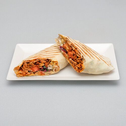 Burrito z grillowanym mięsem, warzywami i sosem, podany na talerzu.