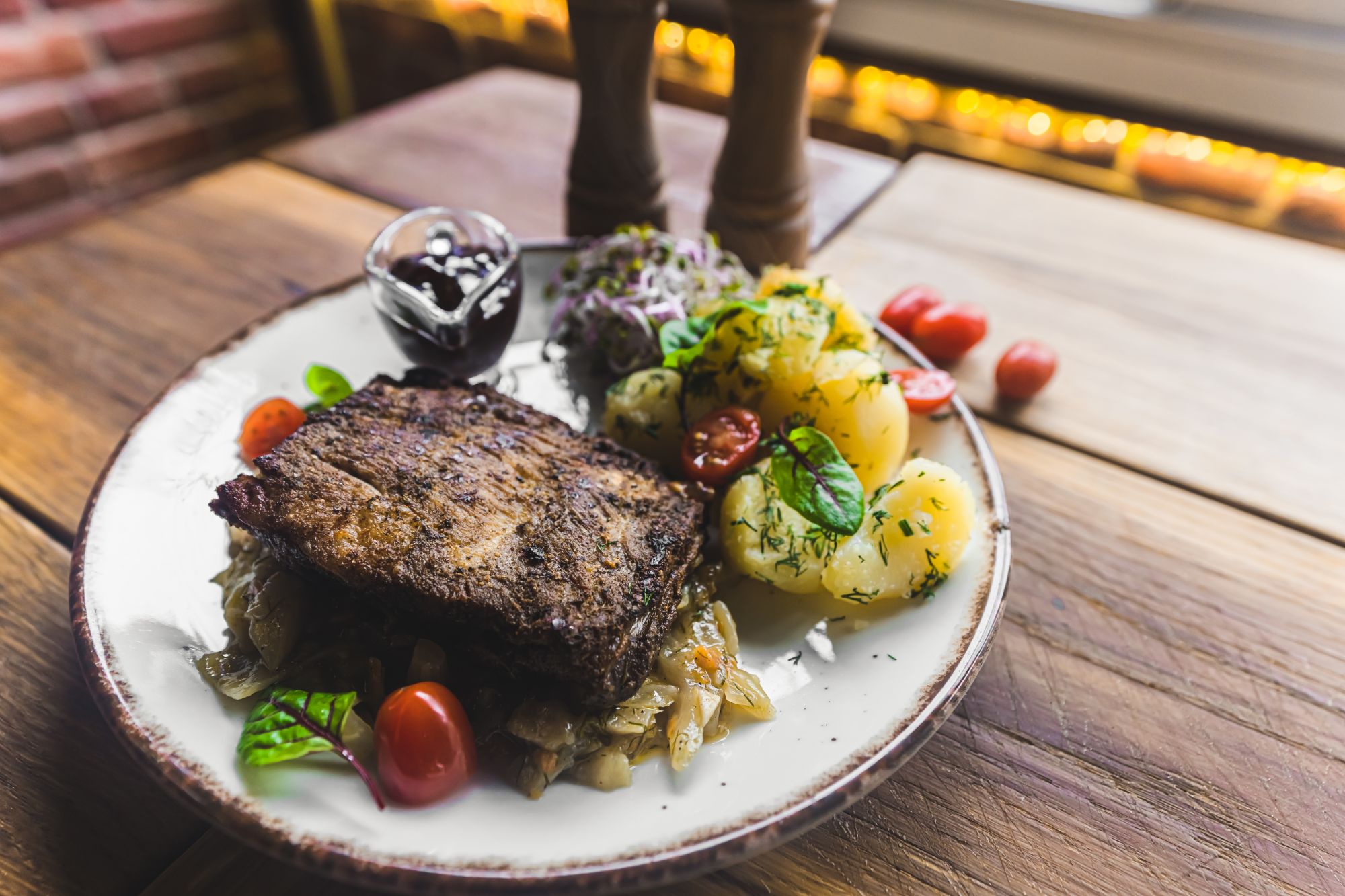 Smażona wołowina na talerzu z ziemniakami, warzywami i sosem, podana w rustykalnej restauracji.