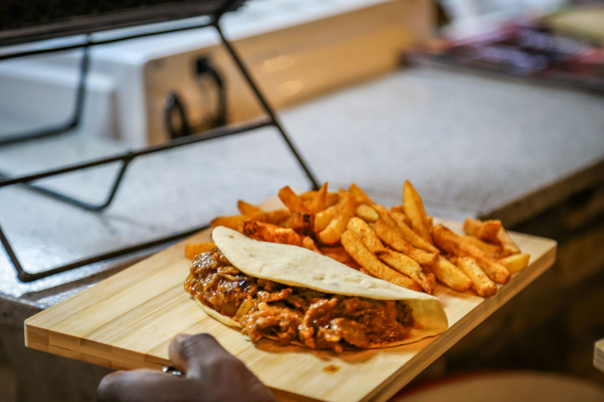 Tacos z mięsem podane z frytkami na drewnianej desce w kuchni.