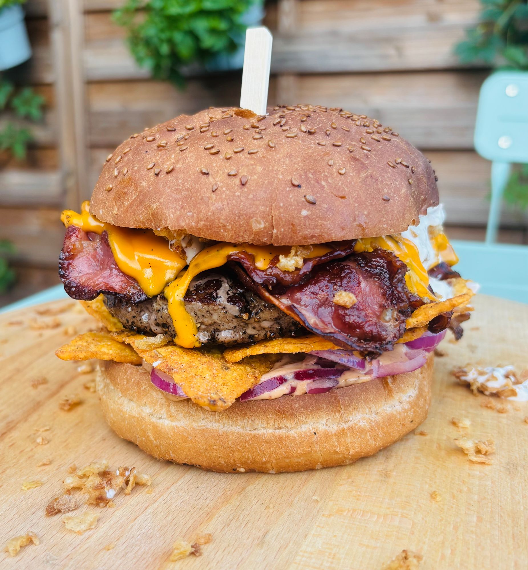 Sociasty burger z wołowiną, serem cheddar, bekonem, chipsami, cebulą i sosem na sezamowej bułce.