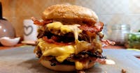 Podwójny burger drwala,2xmięso, ser mozzarella , bekon grillowany, sałata, pomidor, ogórek ,cebulka prażona
