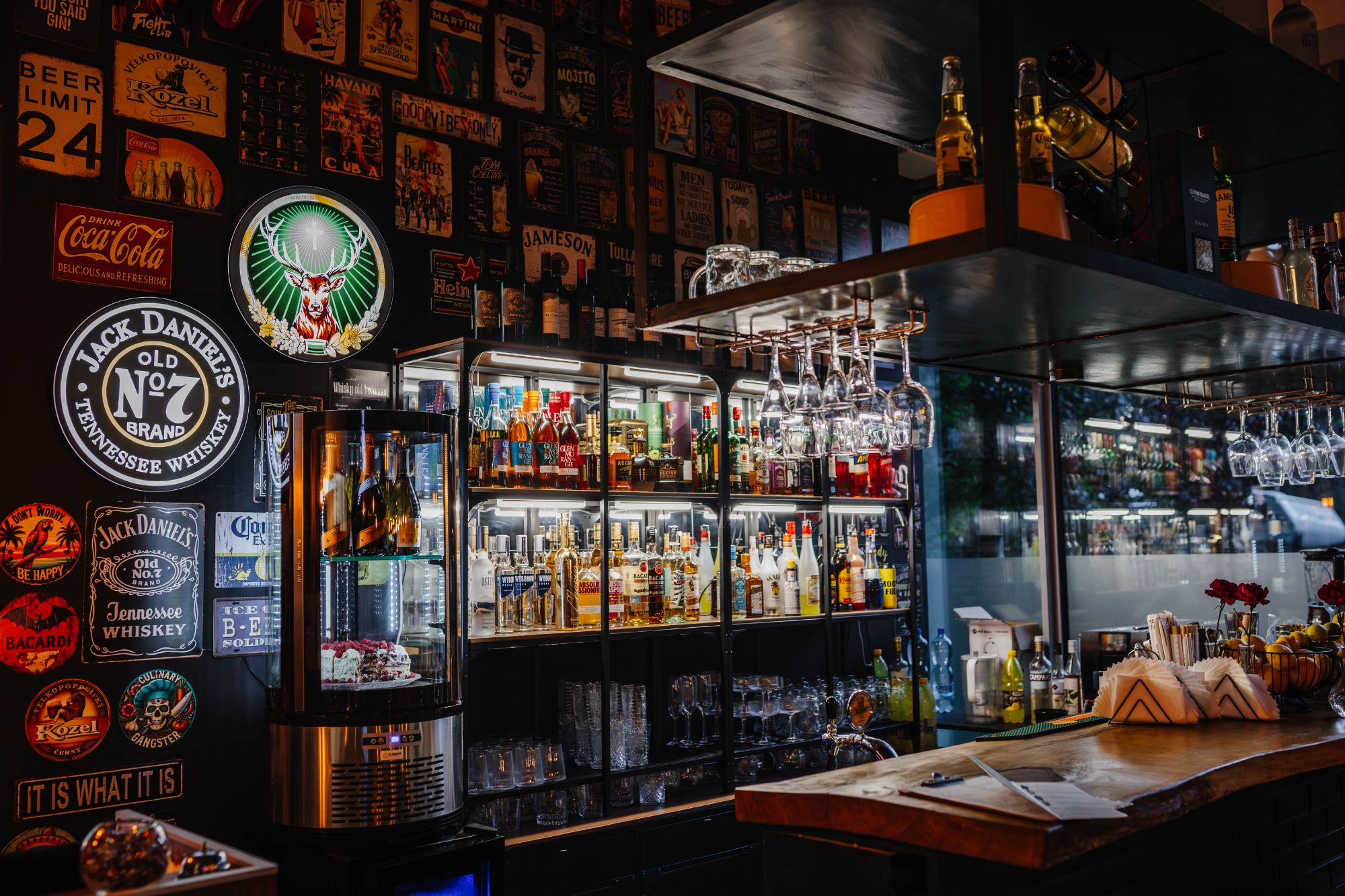 Elegancki bar z półkami pełnymi alkoholi, dekoracjami na ścianach i lampkami nad ladą.