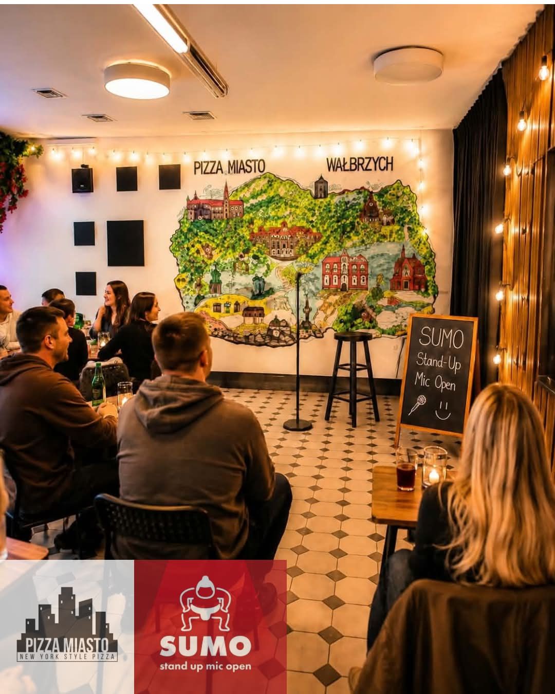 Wnętrze lokalu z mapą Wałbrzycha na ścianie, ludzie siedzący przed sceną na występie stand-up.