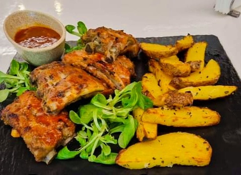 Coaste de porc cu sos barbeque servite cu cartofi cu rozmarin