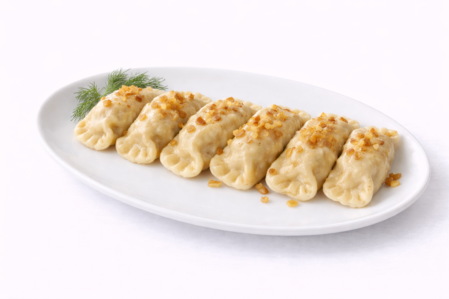 Pierożki na talerzu, posypane chrupiącą cebulką, podane z gałązką koperku.