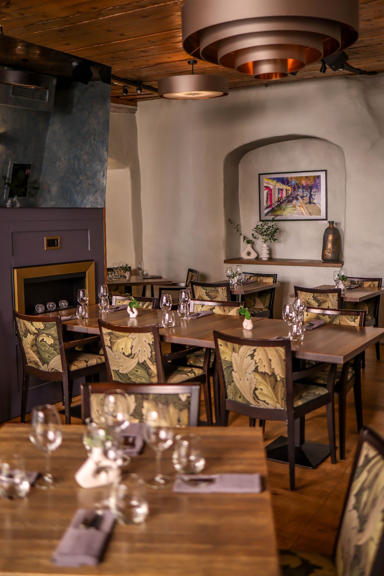 Elegancka restauracja z drewnianymi stołami, ozdobnymi krzesłami i wystrojem w subtelnych odcieniach.