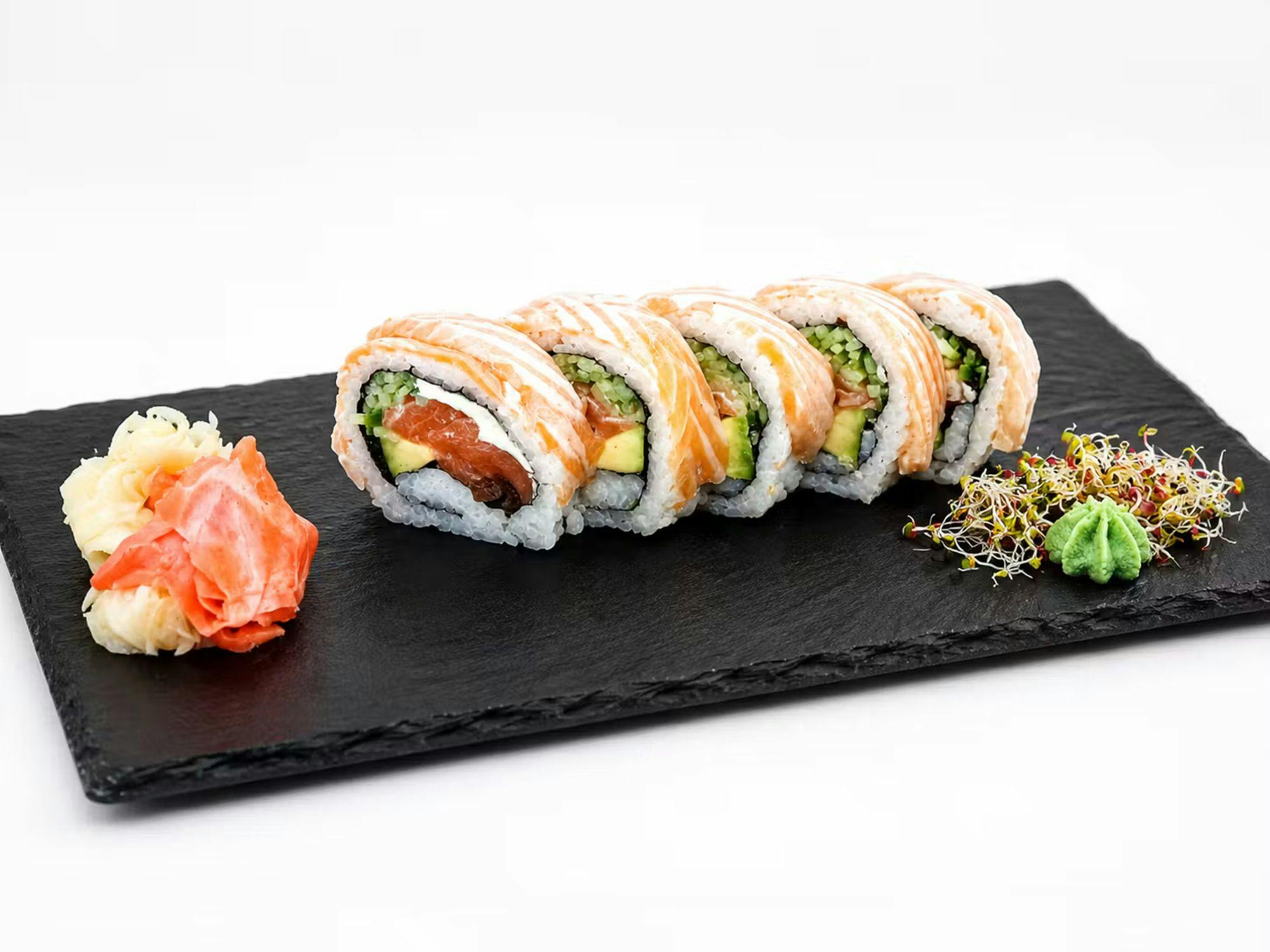 Sushi z łososiem, awokado i warzywami na czarnej kamiennej desce