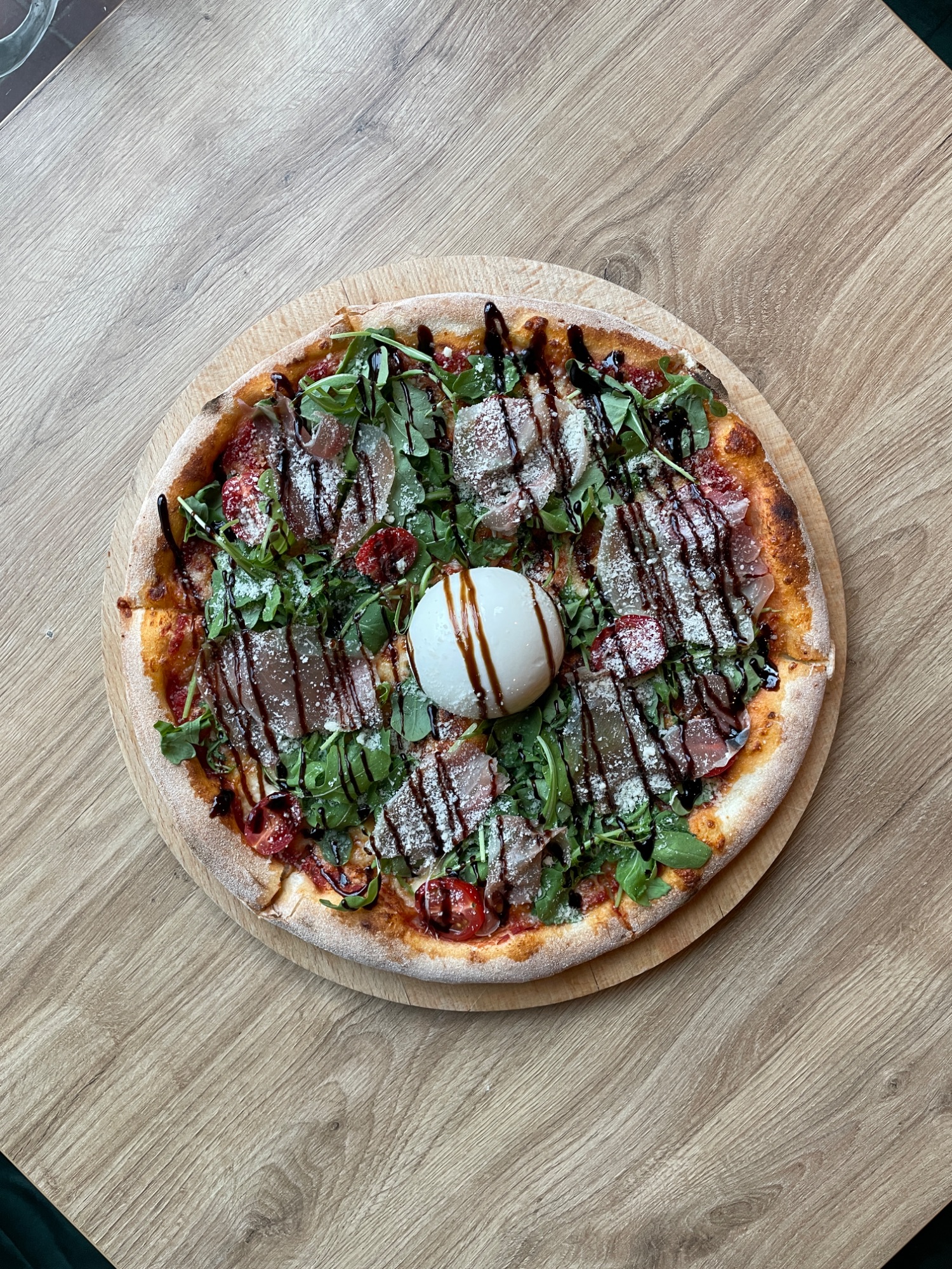 Pizza z serem mozzarella, świeżą bazylią, pomidorami i sosem balsamicznym na drewnianej desce.
