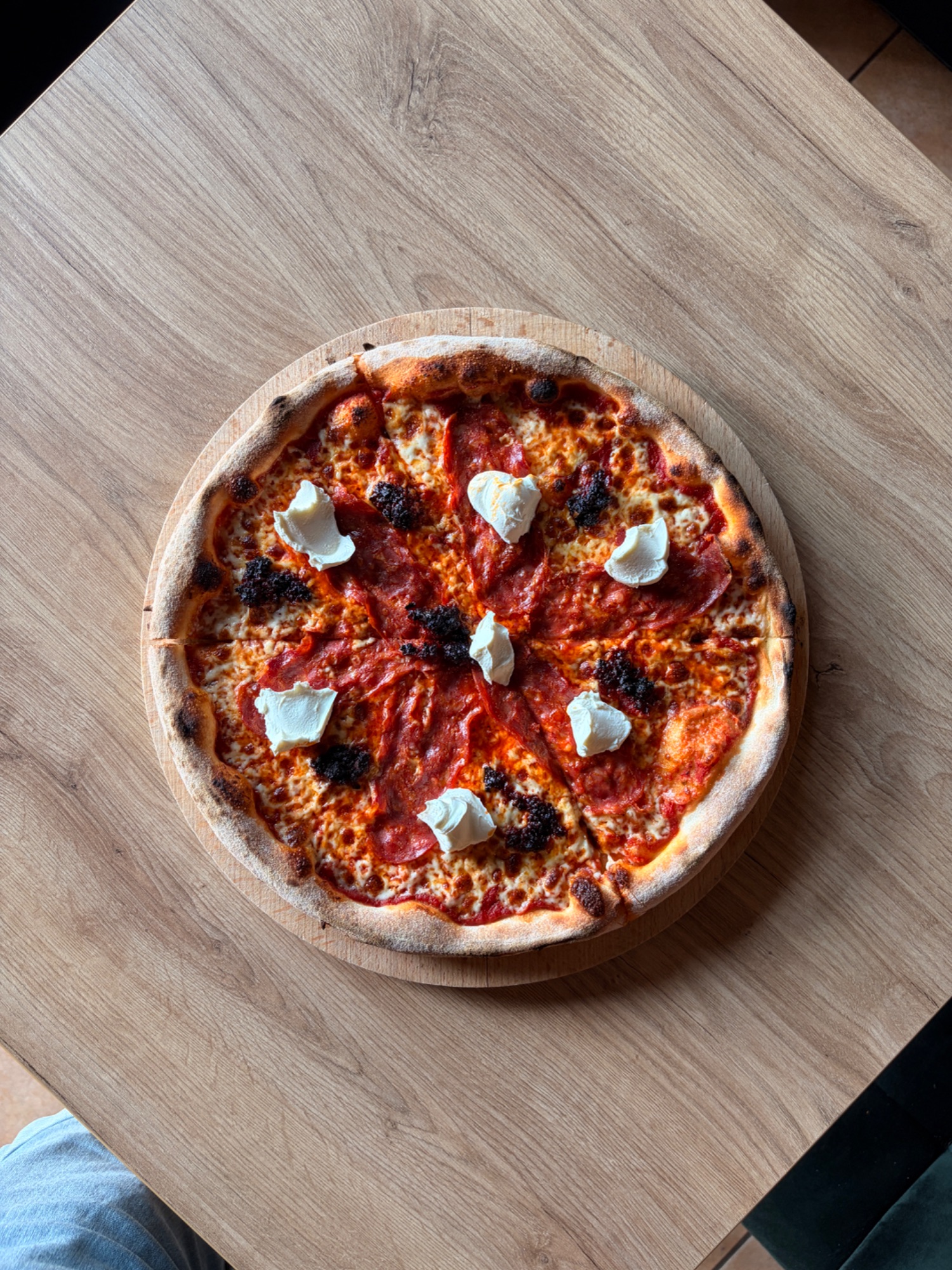 Pizza na drewnianej desce, z sosem pomidorowym, serem mozzarella i kawałkami bekonu.