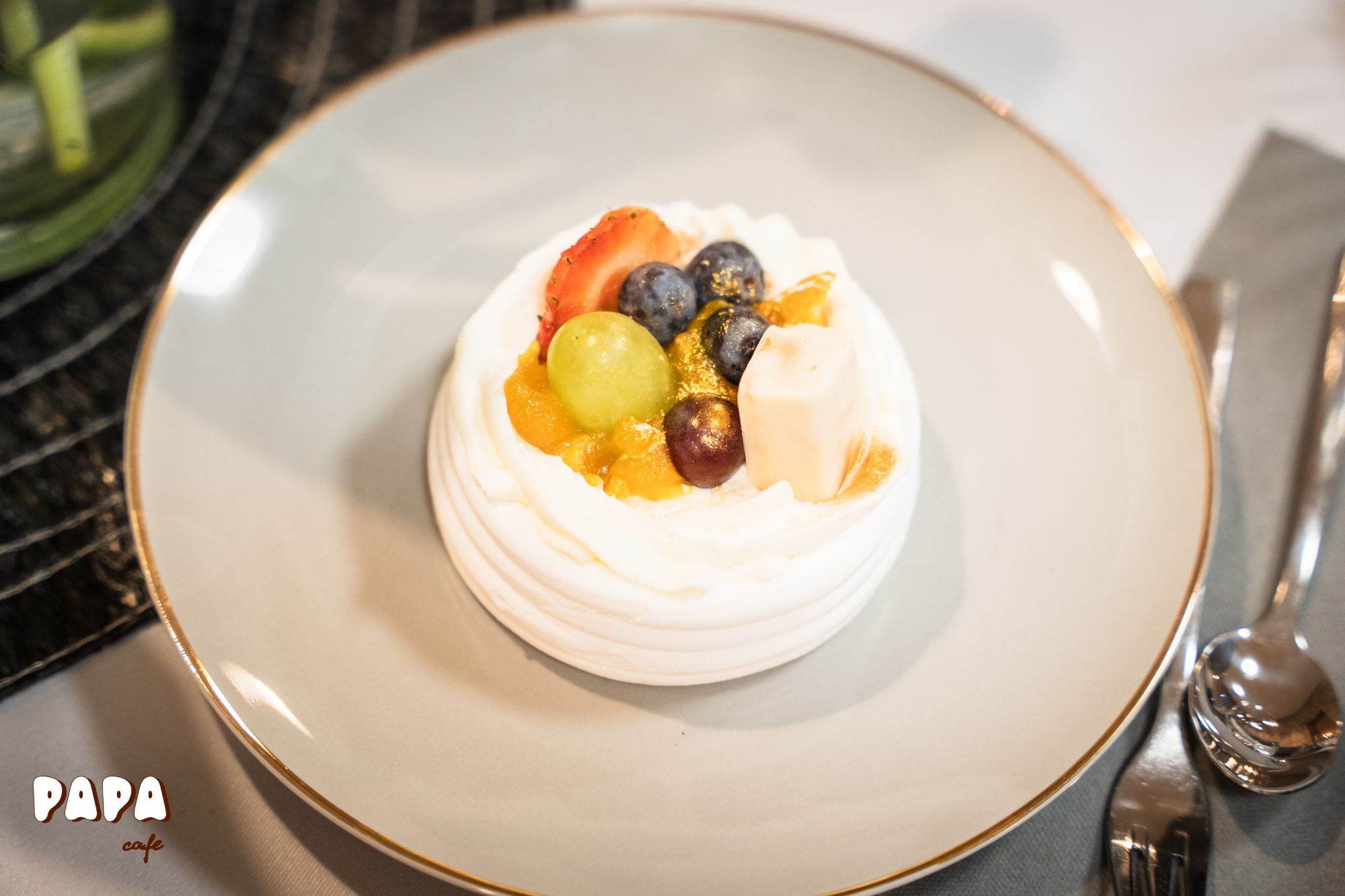 Pyszny deser z bitą śmietaną, owocami i meringue na talerzu w kawiarni Papa.