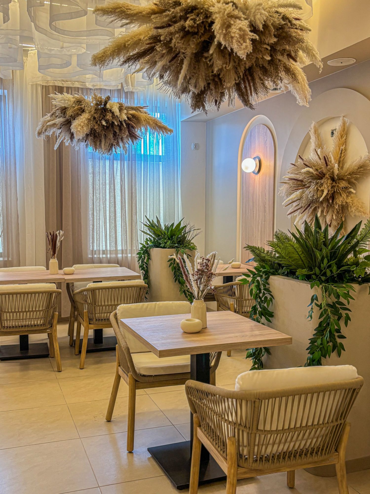 Nowoczesna restauracja z roślinami, miękkim oświetleniem i stylowymi stołami oraz krzesłami.
