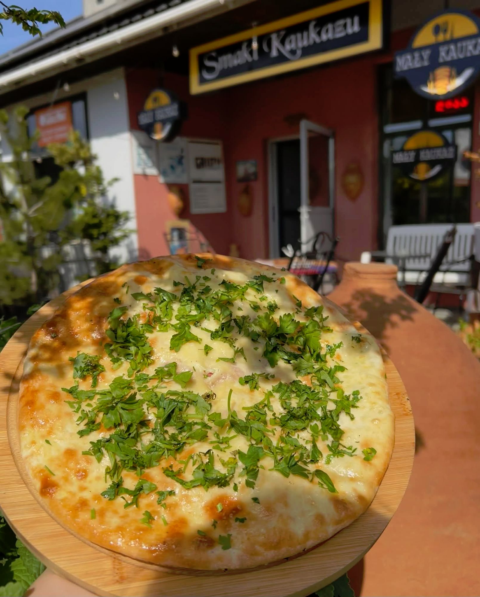 Serwowany chleb z serem z ziołami na drewnianej desce przed restauracją Smaki Kaukazu.
