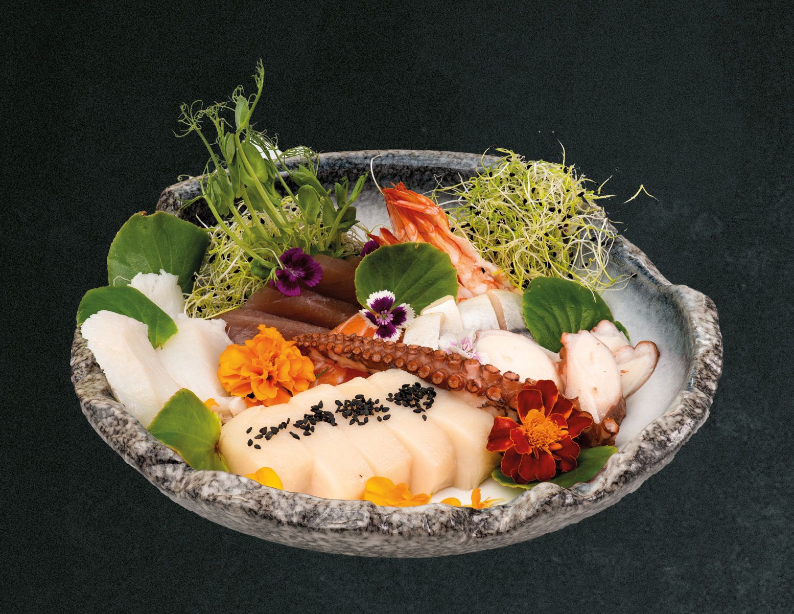 Elegancka miska sushi z owocami morza, kolorowymi kwiatami i świeżymi ziołami na ciemnym tle.
