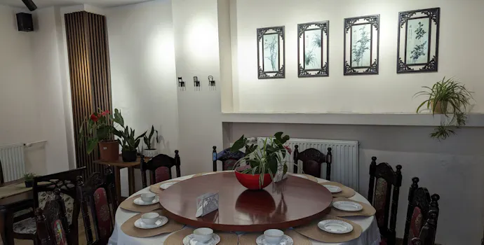 Stół okrągły z nakrytym obiadem, otoczony krzesłami, w elegancko urządzonym wnętrzu restauracji.
