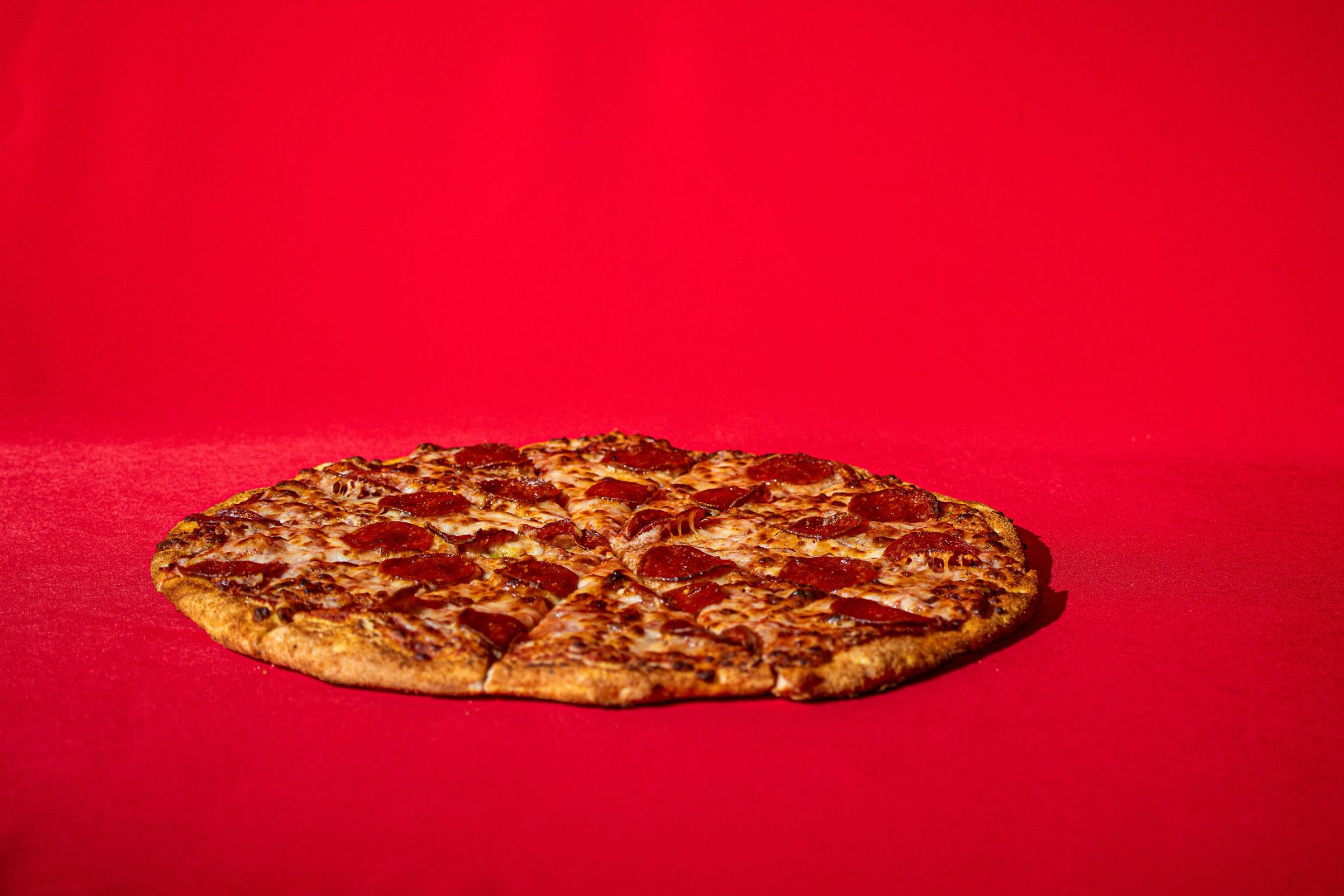 Pizza pepperoni na czerwonym tle.