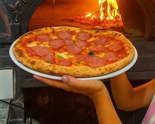 Pizza na tle pieca kamiennego opalanego drewnem bukowym