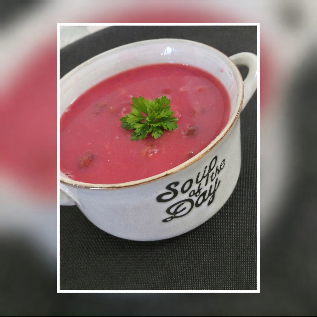 Zupa o różowej barwie, podana w białej misce z napisem "Soul of the Day", ozdobiona świeżą pietruszką.