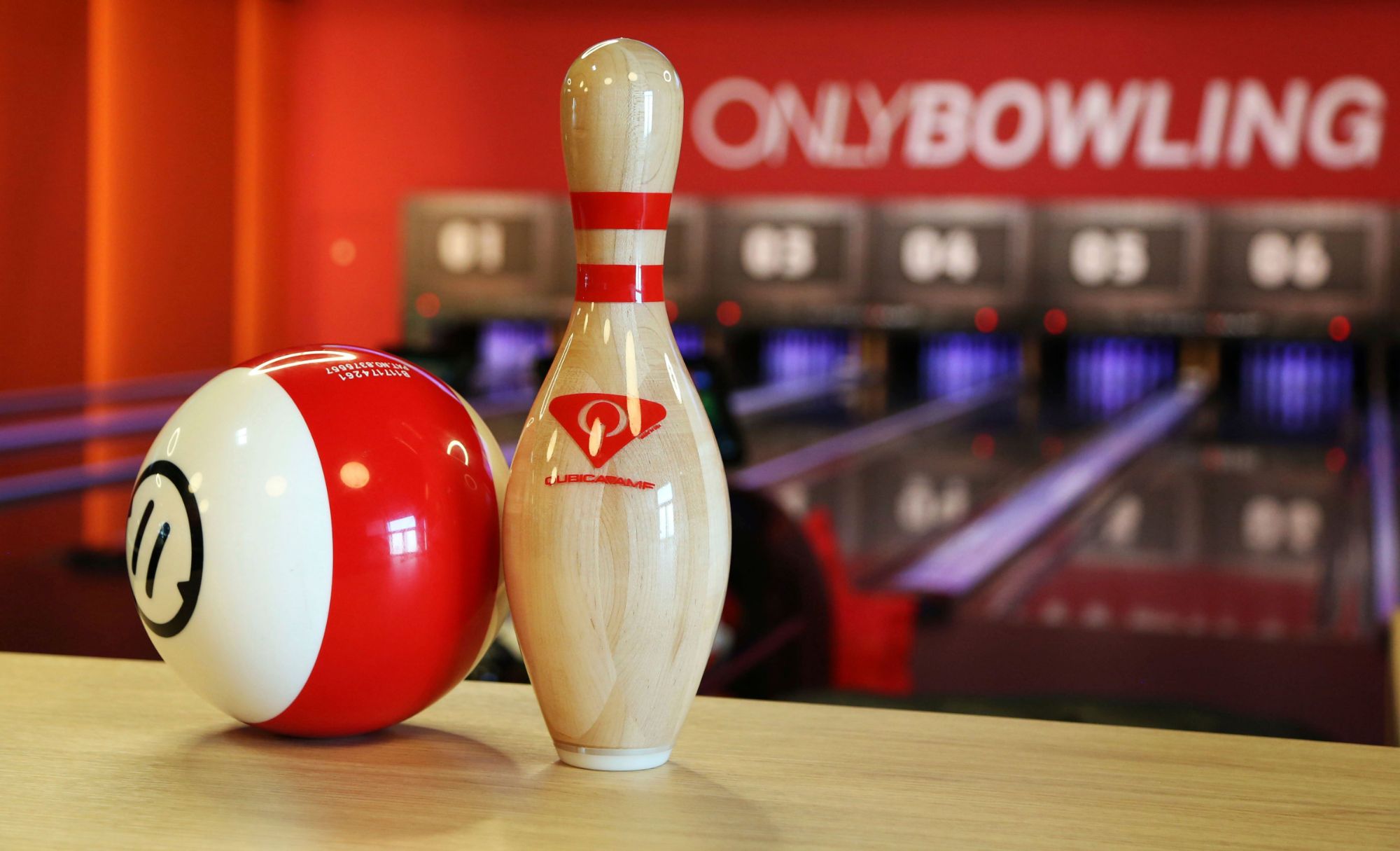 Kule bowlingowe i kręgiel na tle torów bowlingowych w tle.