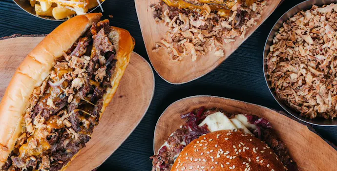 Zasitan obrok s burgerima, hot dogom, pomfritom od slatkog krumpira i prelivom od sira.