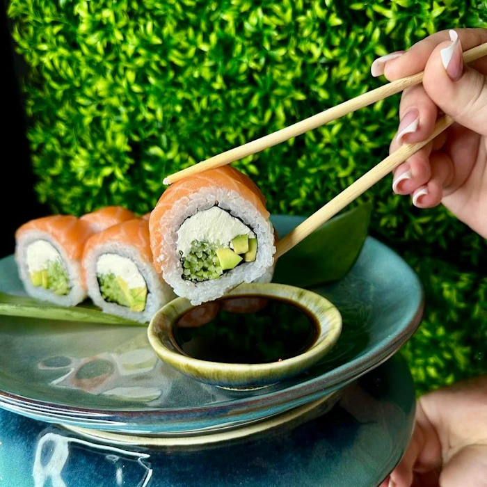 Hand dipping sushi roll in soy sauce