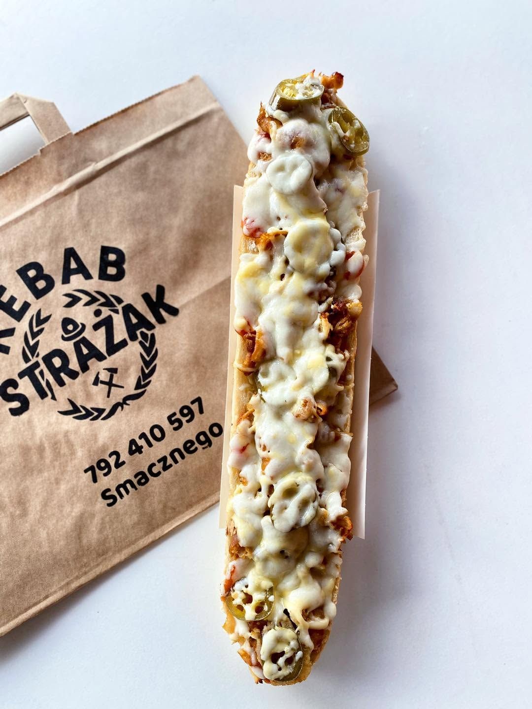 Długi kebab z serem, piklami i przyprawami, w torbie z logo "Kebab Strażak".