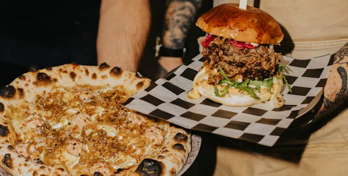 Pizza i burger z serem, warzywami i mięsem, serwowane na talerzu w stylowej restauracji.