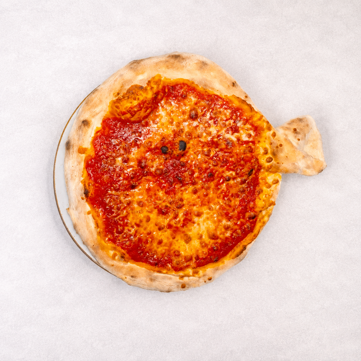 Pizza w kształcie ryby pokryta sosem pomidorowym i serem, na jasnym tle.