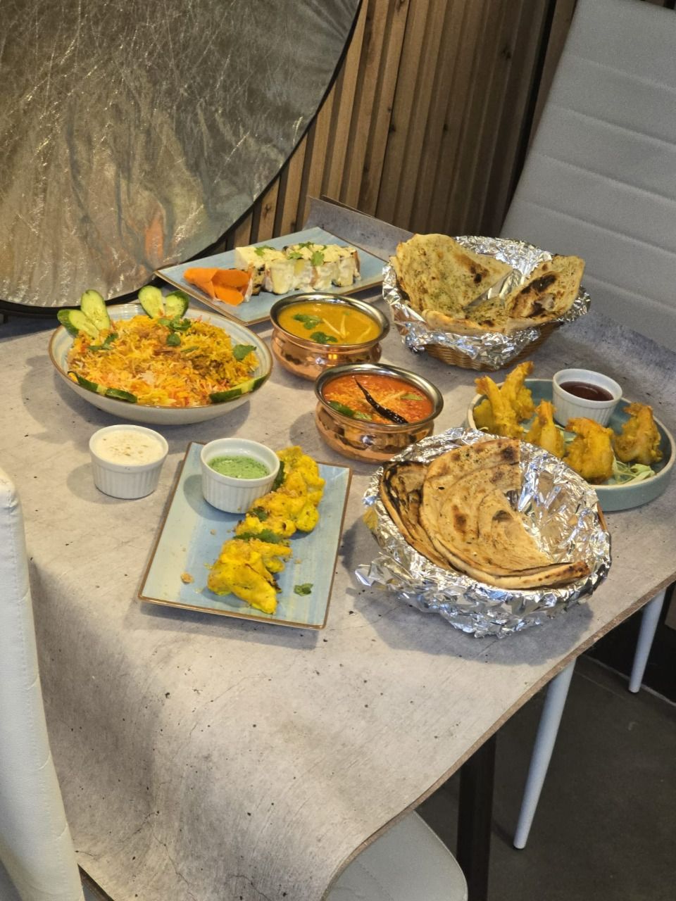 Stół z różnorodnymi potrawami indyjskimi, w tym curry, naan, samosa i sałatką.