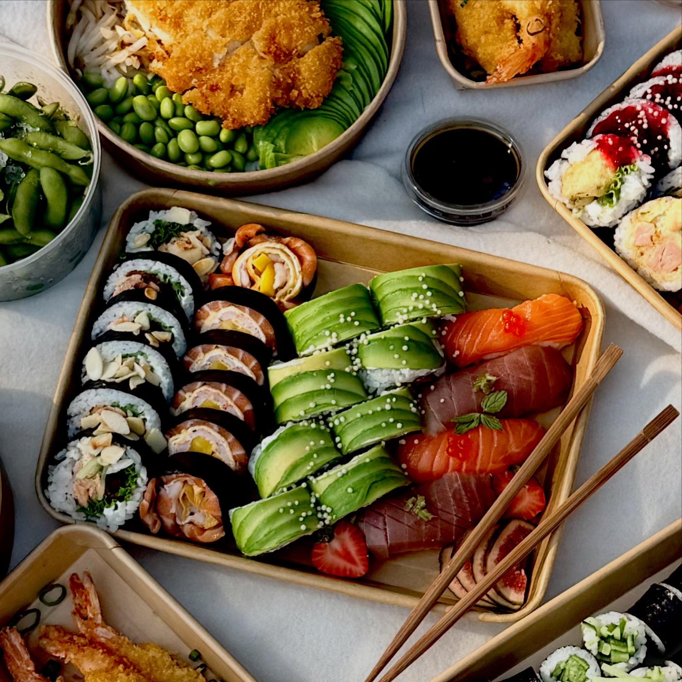 Pyszne zestawienie sushi, tempura, edamame i sałatek w eleganckiej prezentacji na stół.