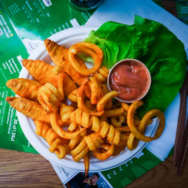 Talerz frytek spiralnych i kawałków kurczaka, podany z sałatą i sosem wśród menu restauracji.