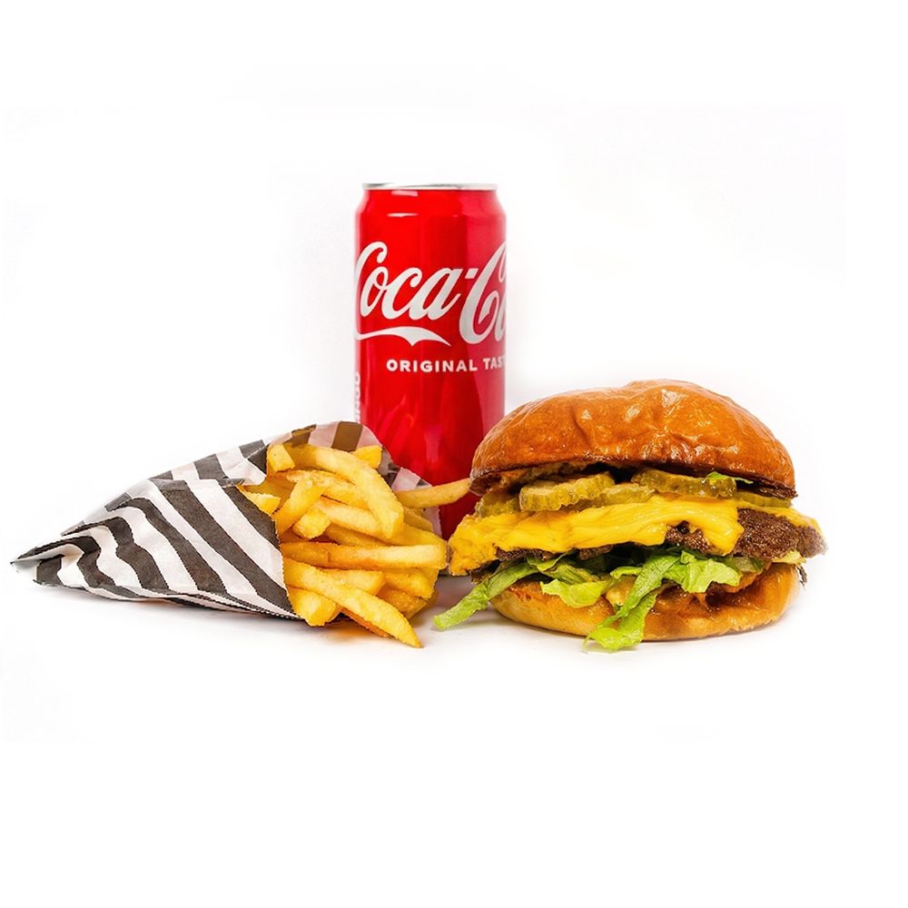 Burger z serem, frytki w torbie, puszka Coca-Coli na białym tle.