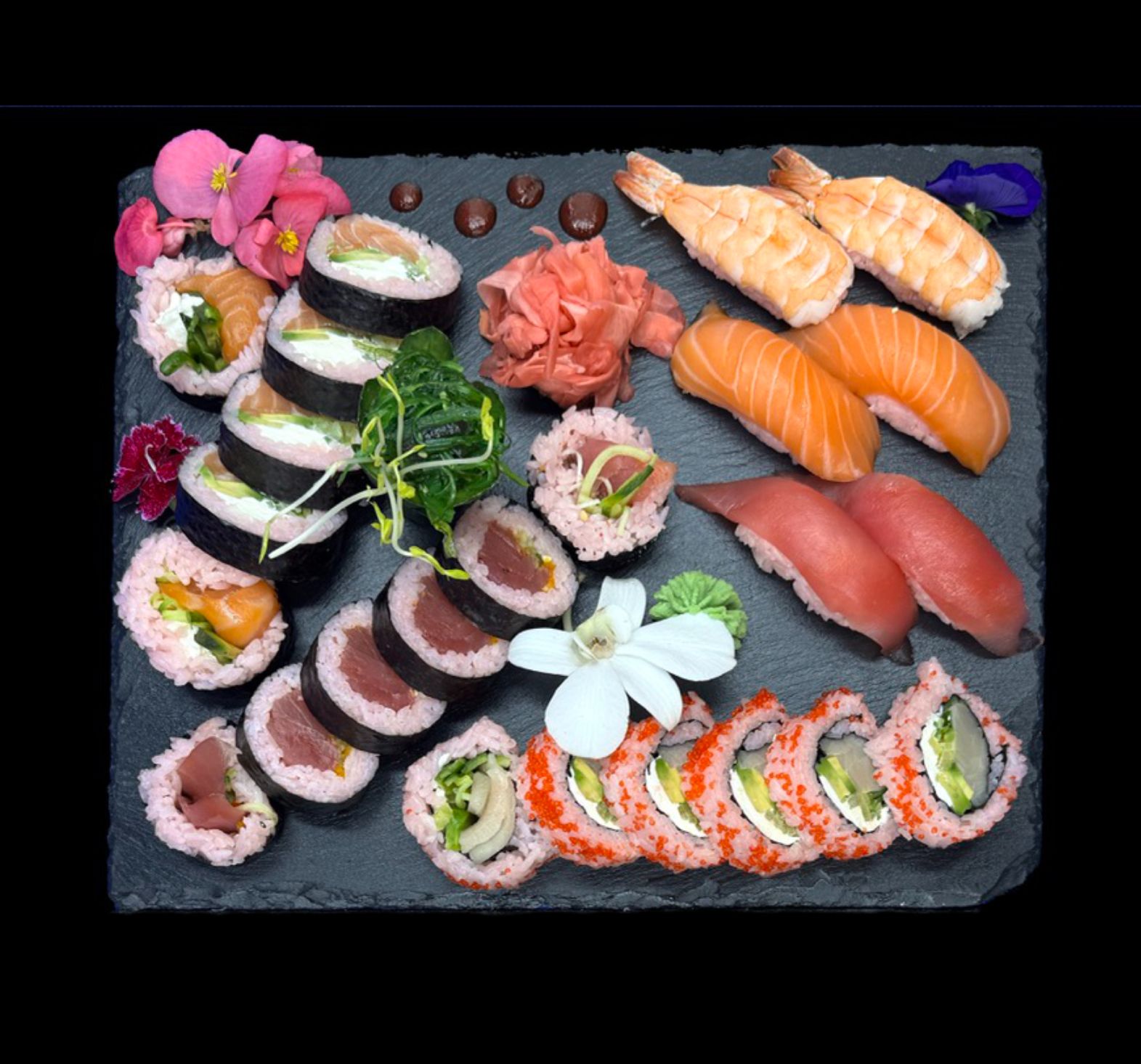Taca sushi z różnymi rodzajami sushi, w tym nigiri, maki i sashimi, udekorowana kwiatami jadalnymi.