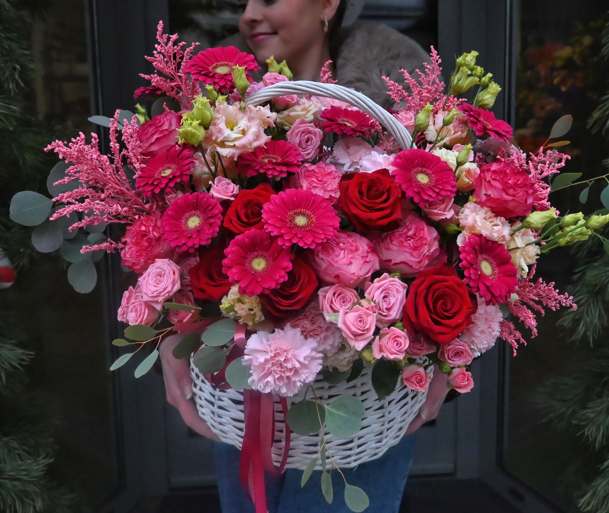Kosz Pełen Miłości Opis: Efektowna kompozycja w koszu z róż, gerber, goździków i kwiatów sezonowych w odcieniach czerwieni i różu.