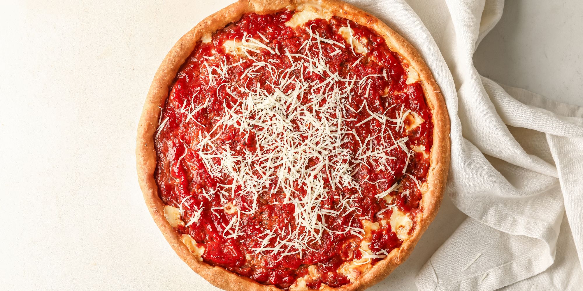 Pizzeria z okrągłą pizzą z sosem pomidorowym i serem na jasnym tle.