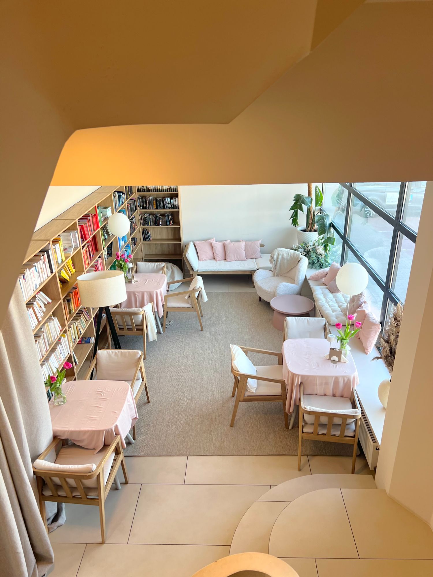 Nowoczesna biblioteka z przytulnymi strefami do czytania, jasnym oświetleniem i roślinami.
