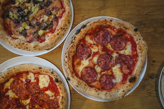 Trzy rodzaje pizzy na talerzach: pepperoni, z serem oraz z mięsem i warzywami.