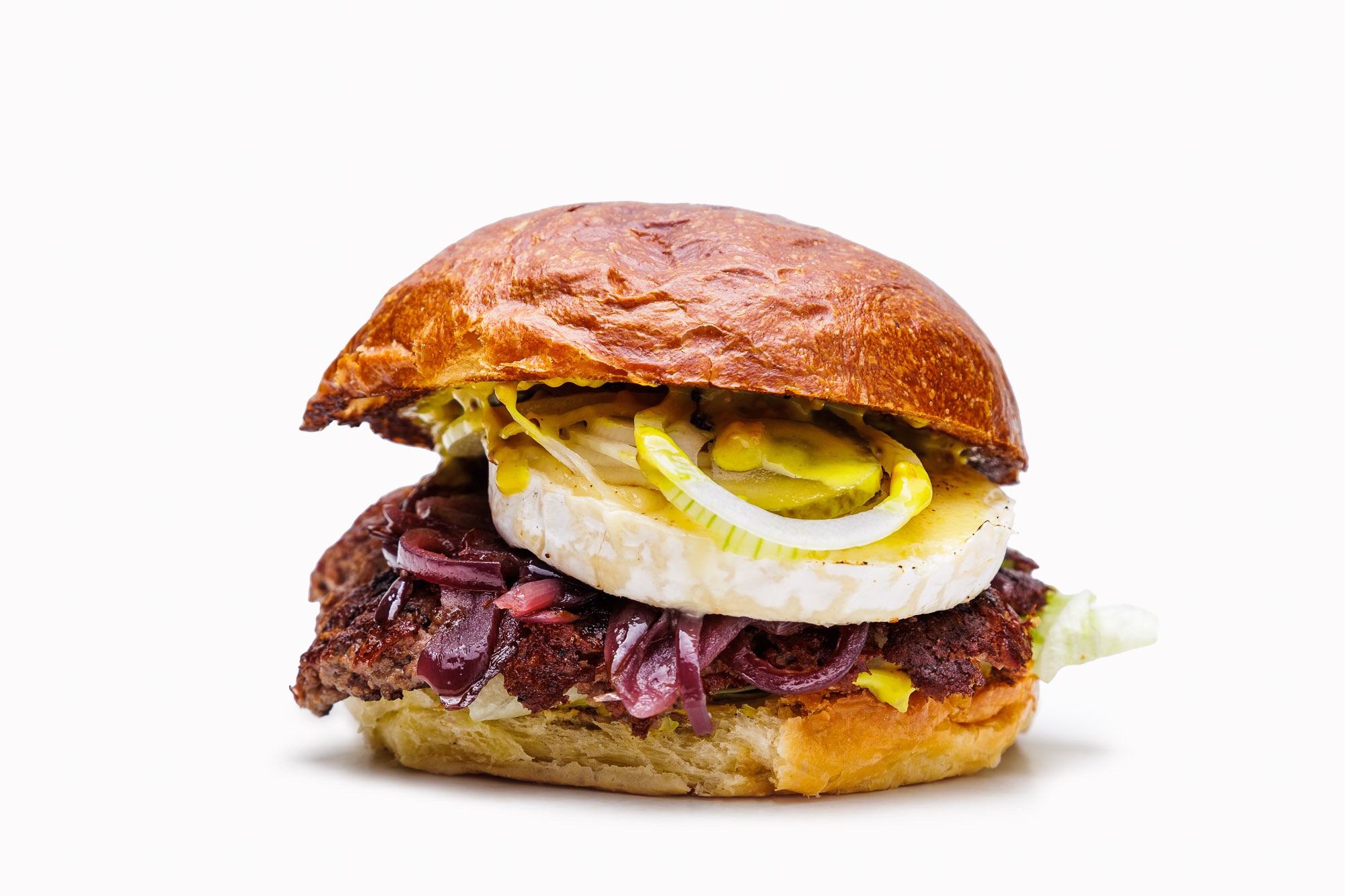 Burger z soczystą wołowiną, serem, cebulą i piklami w złocistej bułce.