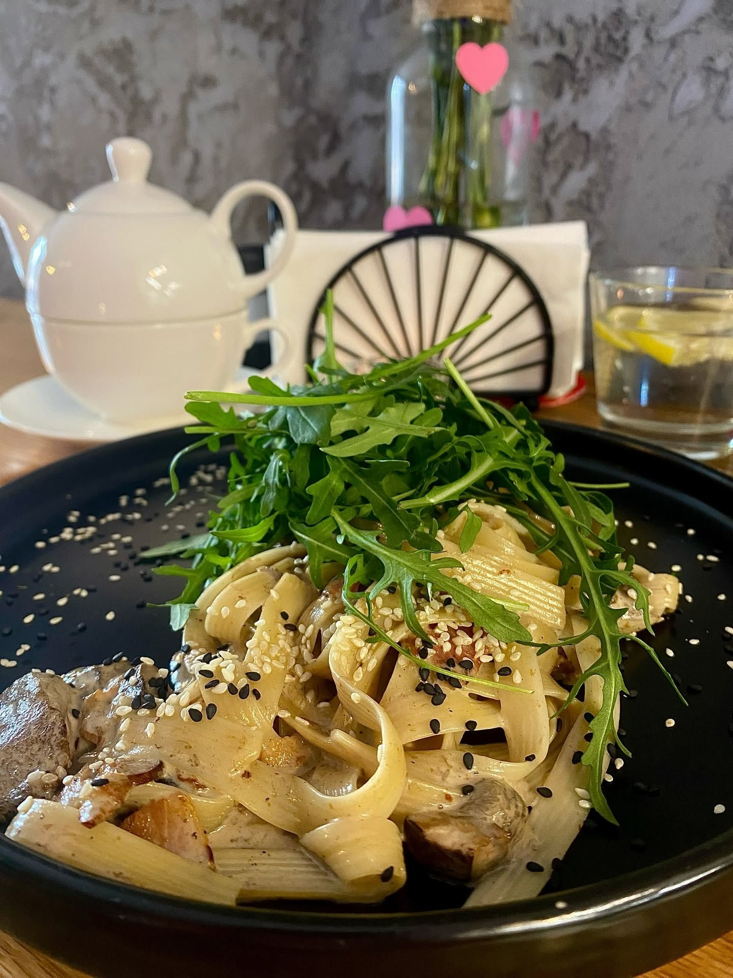 Makaron z sosem, mięsem i rukolą, posypane sezamem, w eleganckiej restauracji.