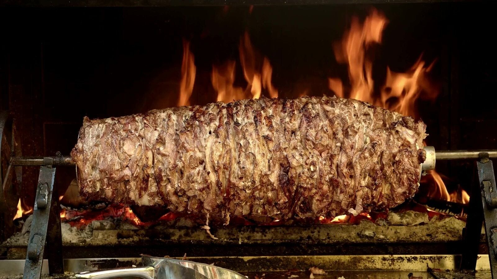 Smalec pieczony na rożnie, otoczony płomieniami, z soczystą skórką i aromatycznym zapachem.