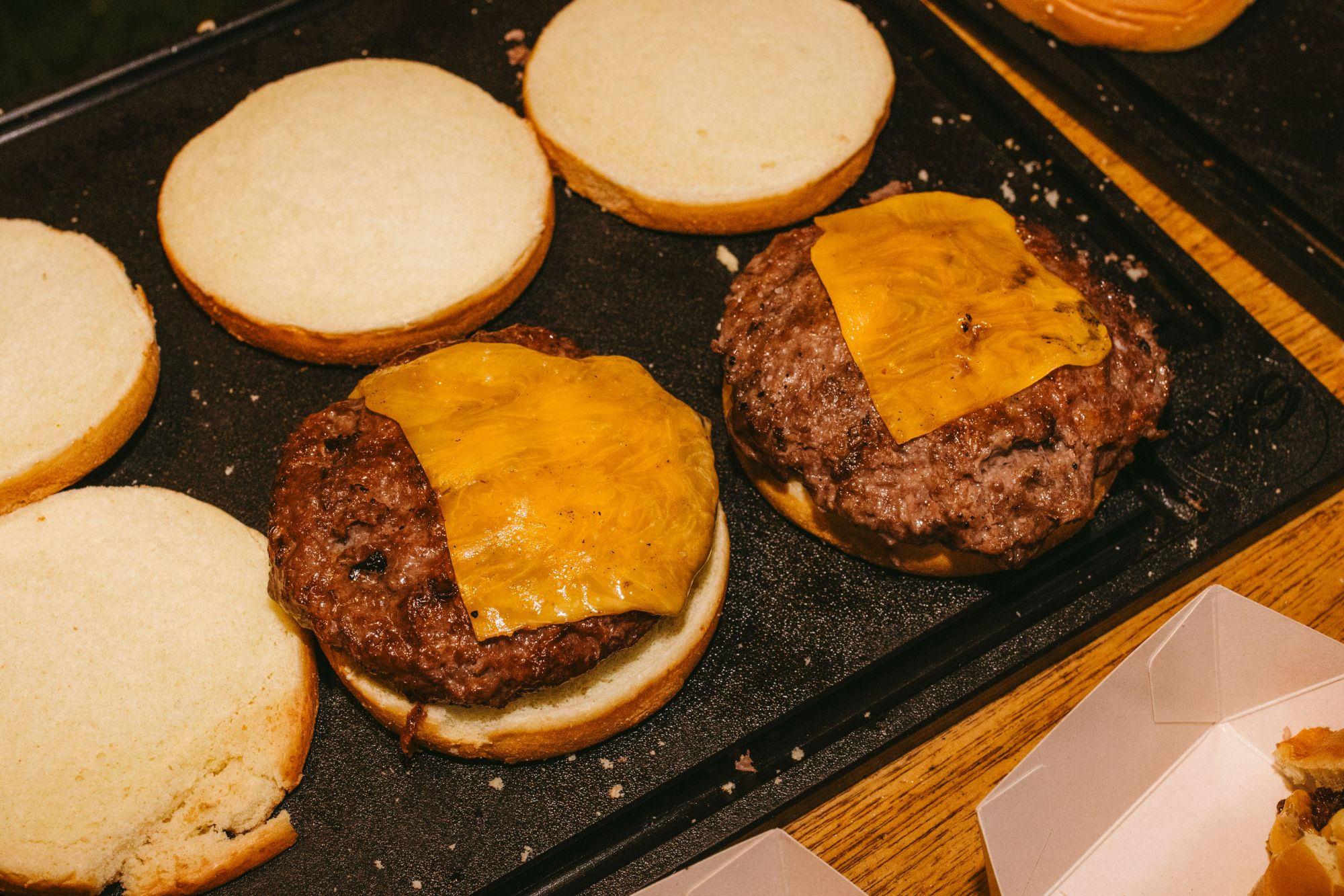 Zbliżenie na kanapki z hamburgerami, jeden z serem cheddar, na drewnianym stole.