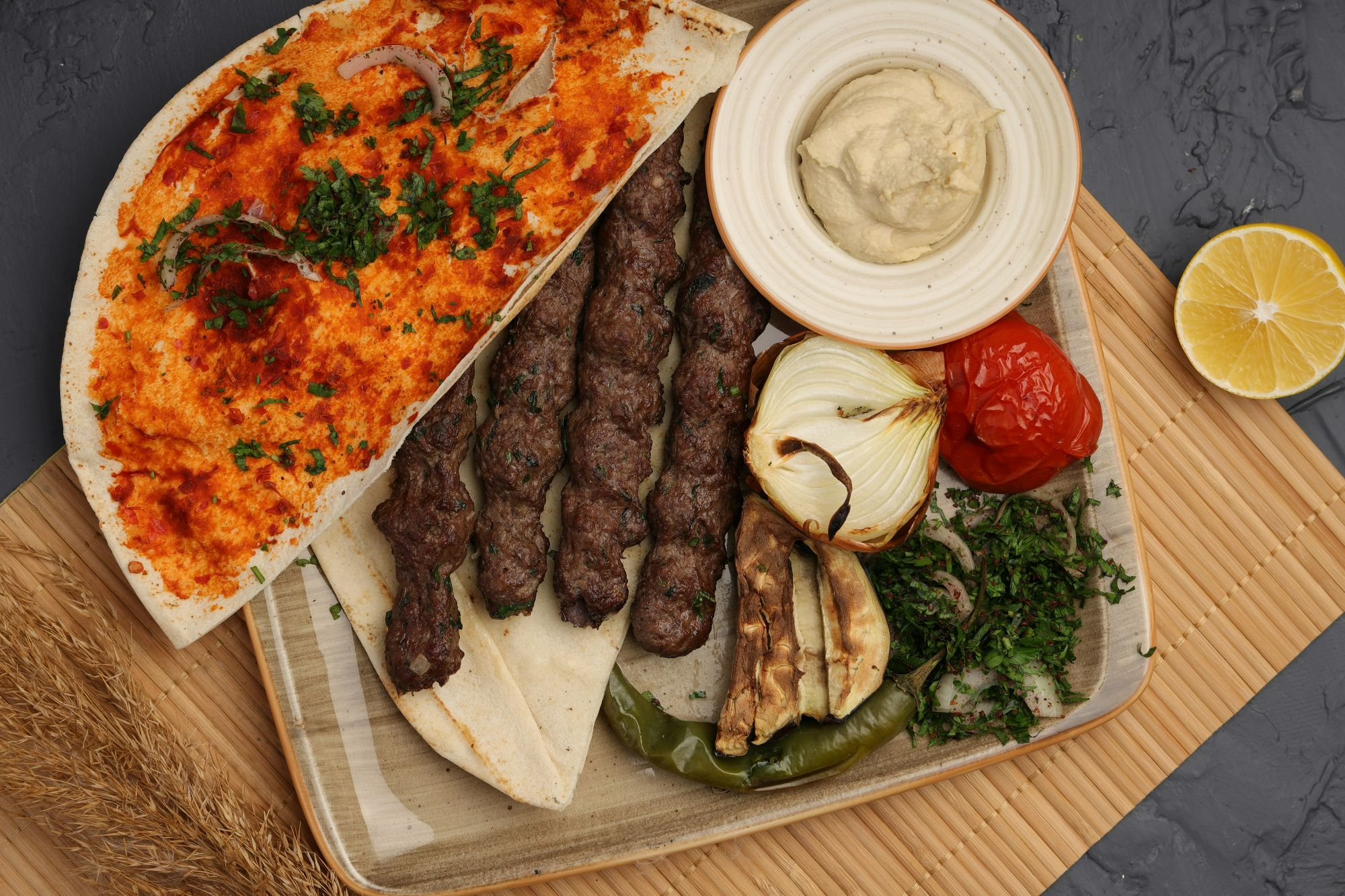 Taczek z mięsem, grillowane warzywa, hummus i cytryna na talerzu.