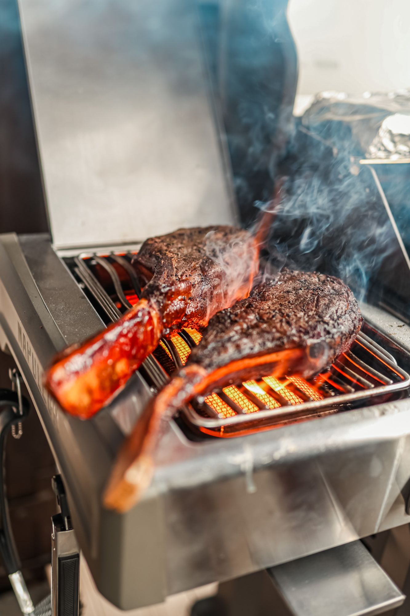 Smażone steki na grillu, dymiące i soczyste, z widocznymi śladami grillowania.