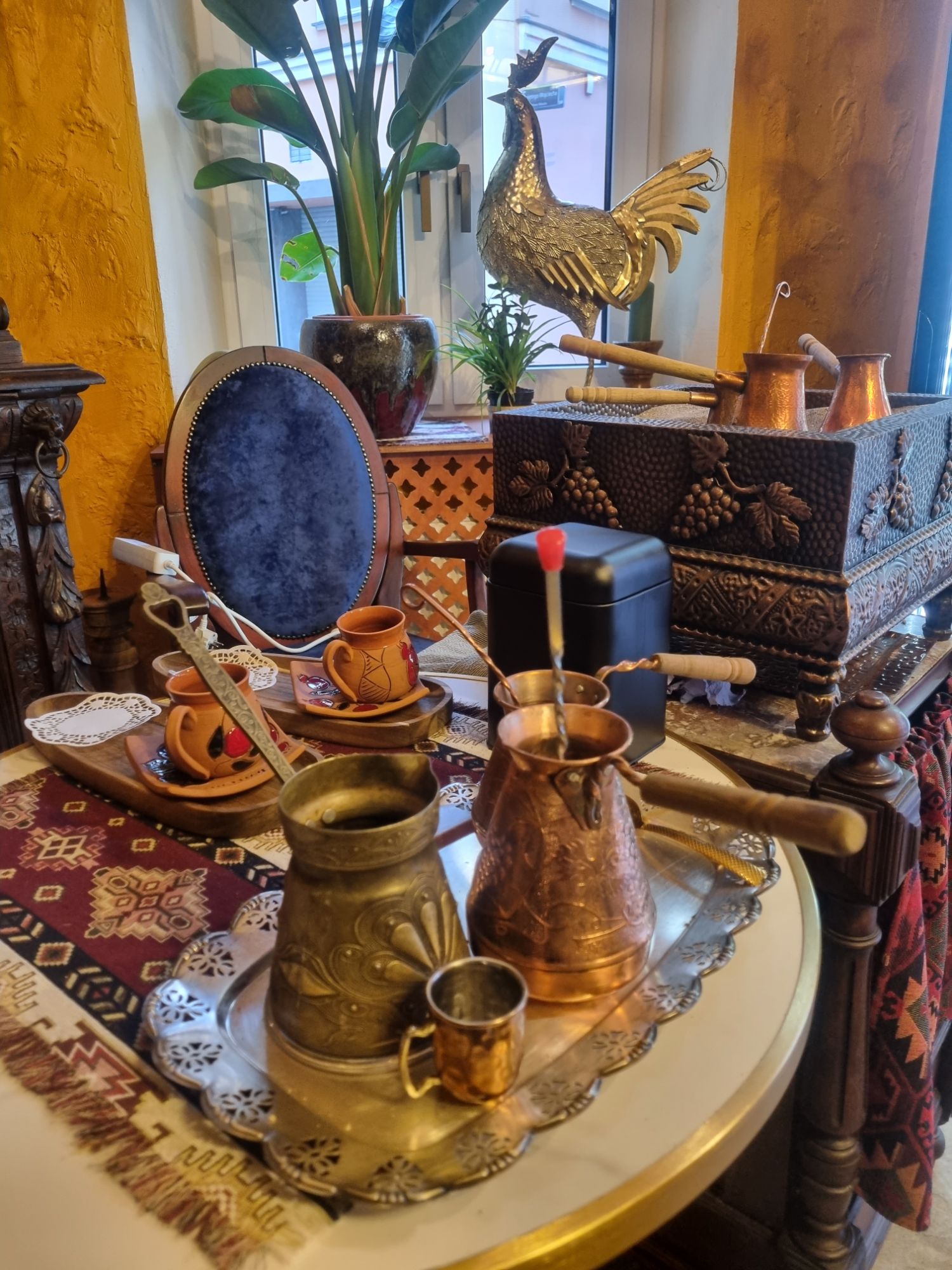 Zestaw mosiężnych i miedzianych naczyń do parzenia kawy na ozdobnym stole w stylu orientalnym.