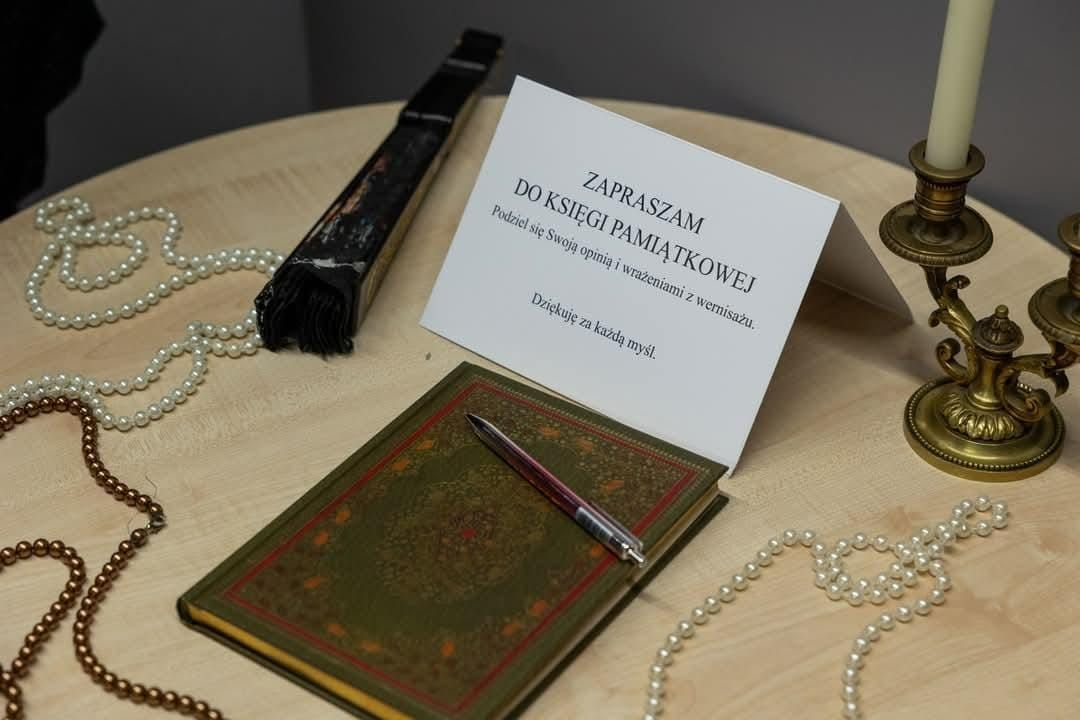 Na stole znajduje się zielona księga, długopis, perły oraz zaproszenie do księgi pamiątkowej.
