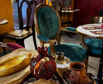 Kawałki pieczywa, filiżanka herbaty i eleganckie krzesła w przytulnej kawiarni z kolorowymi ścianami.
