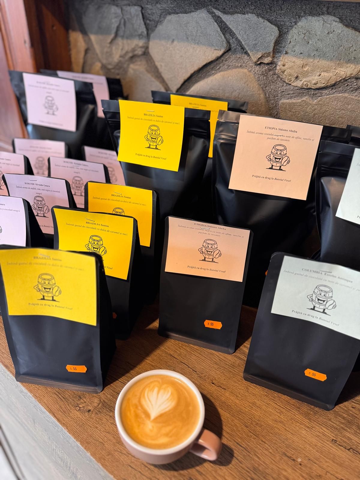 Diverse pungi de cafea pe un raft de lemn, cu o ceașcă de cafea deasupra, decor pentru un local cozy.