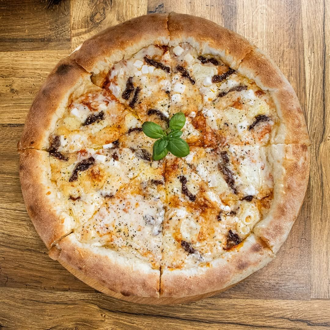 Pizza z serem, sosem pomidorowym, cebulą i bazylią na drewnianym stole.