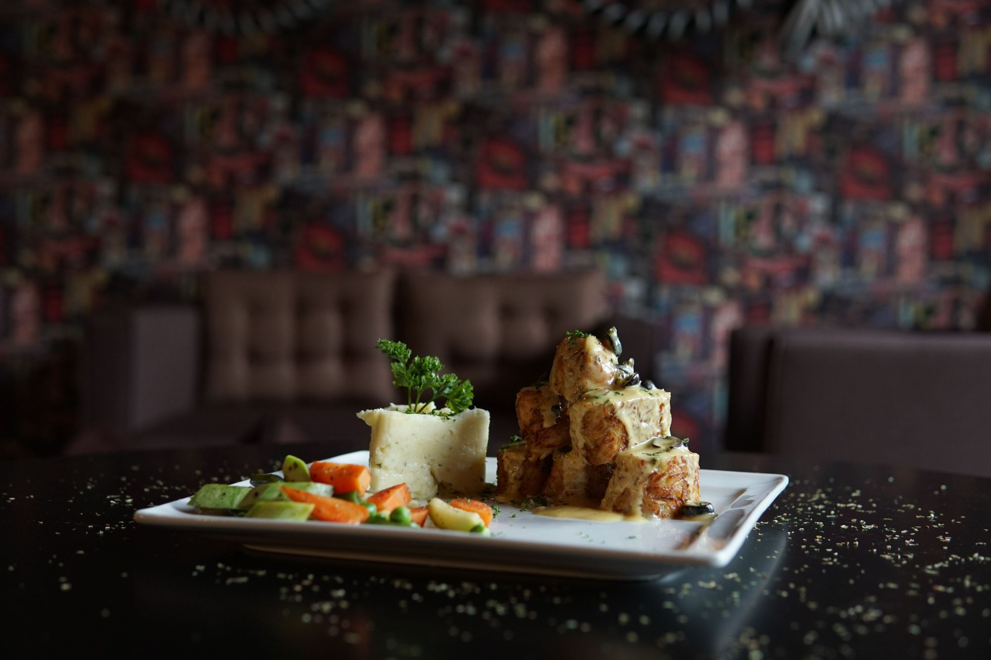Talerz z potrawą z ziemniaków, warzywami i ziołami na tle stylowej restauracji.